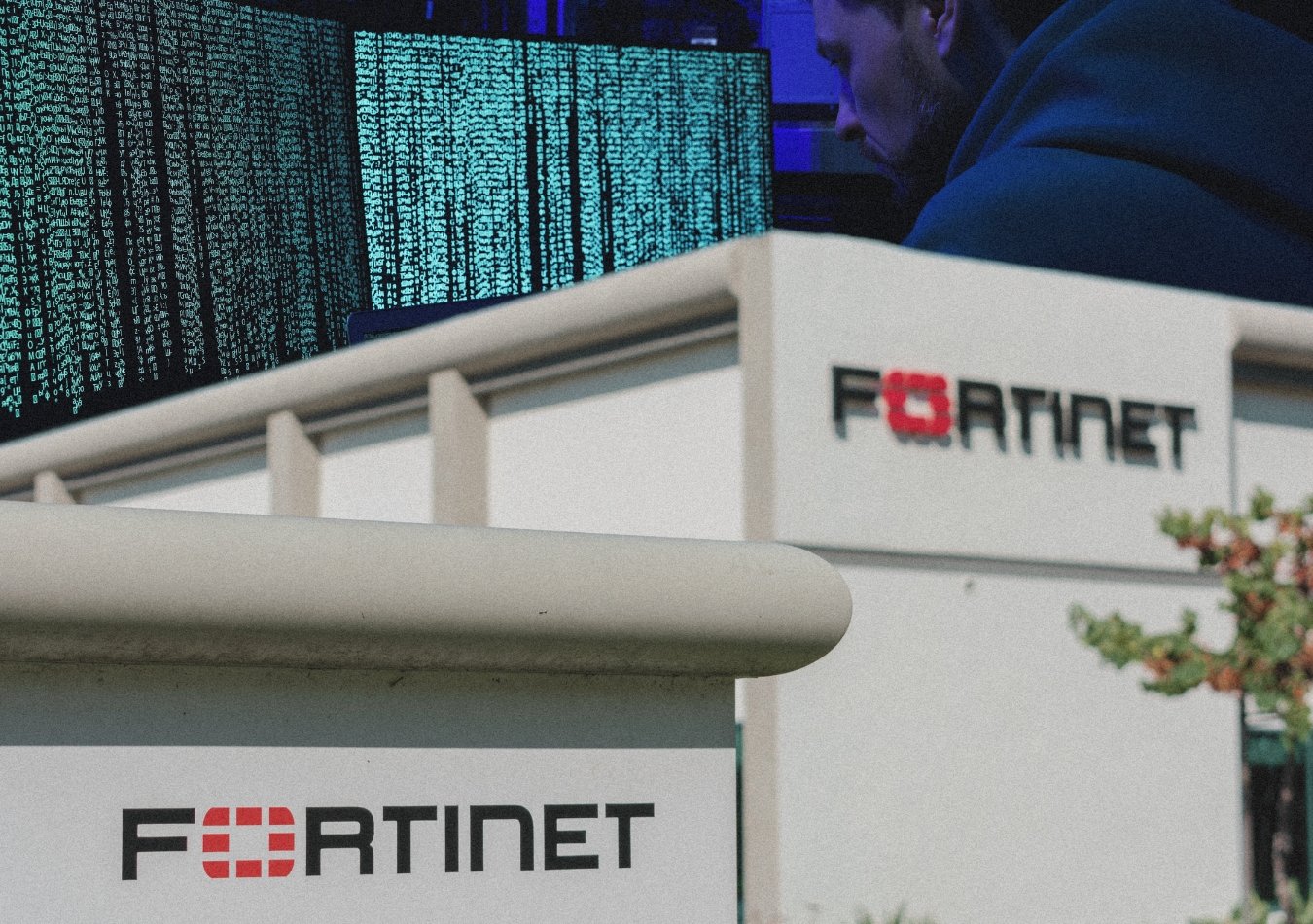 fortinet data leaked for free. image shows fortinet office in the front and a cybercriminal kacking into systems in the background