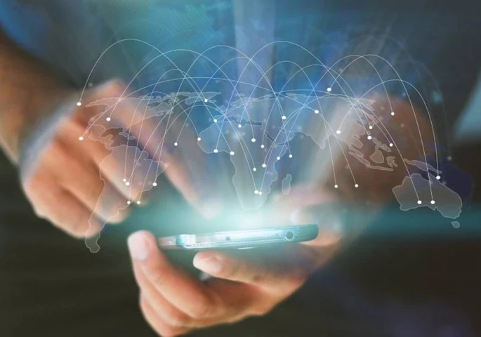 Person holding a smartphone with a see-through global map imposed on it.