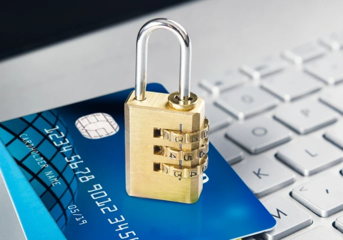 A lock sitting on top of a card that's laying on a keyboard.