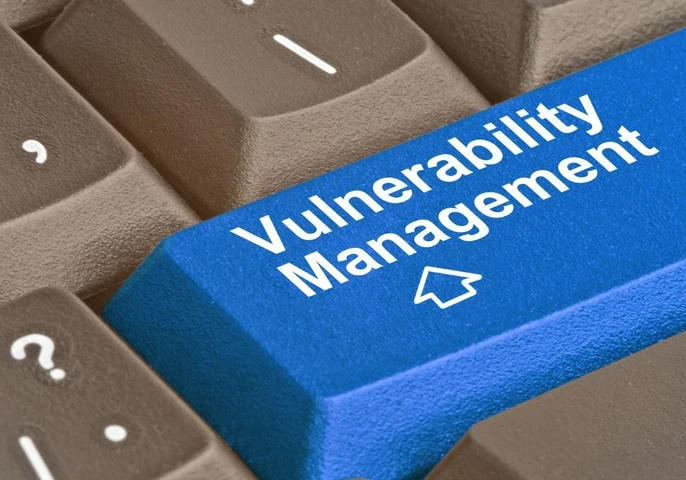 Close up of keyboard keys with a bright blue key in the middle showing the words "Vulnerability Management"