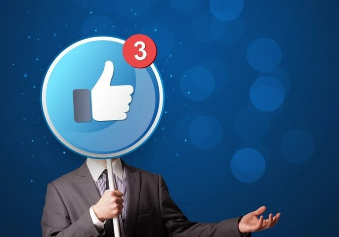 Image showing a man dressed in a suit holding up a large lollipop sign with a thumbs up emoji and sign for 3 unread notifications in Facebook branding