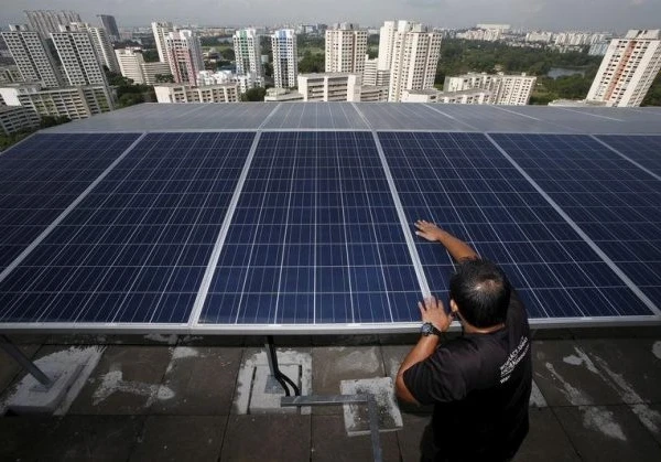 Engineer fitting solar panels to the roof of a skyscraper with the Singapore cityscape in the background