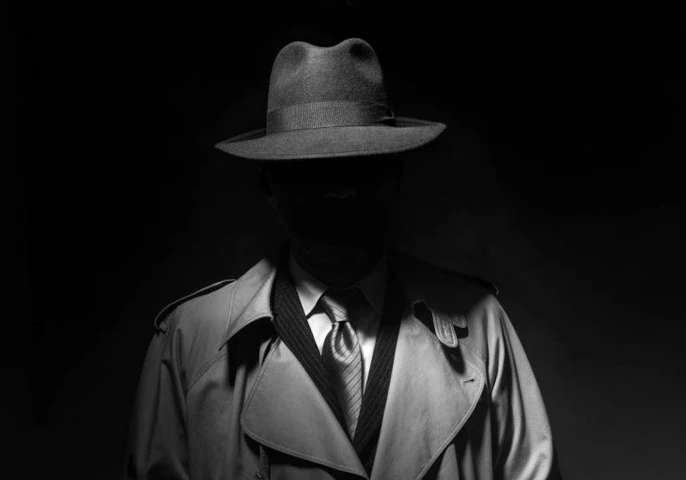 Mysterious spy lurking in the shadows in a trench coat.