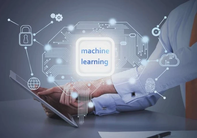 The words "machine learning" against a circuit board imagery and a person working on a tablet at a desk in the background.