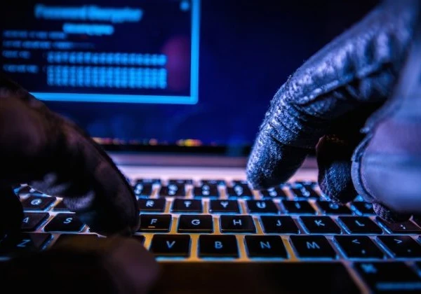 Gloved hands typing on a laptop to show a hacker working