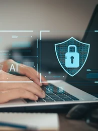 A businessman typing on a laptop with icons floating around it depicting online security.