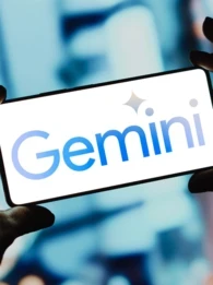Person holding up a smartphone and the screen is displaying the Google Gemini logo against a Bokeh background.