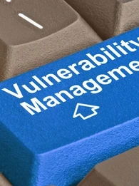 Close up of keyboard keys with a bright blue key in the middle showing the words "Vulnerability Management"