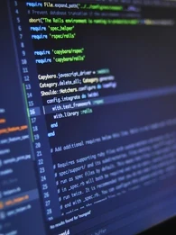 Code on a laptop screen in a dark room.