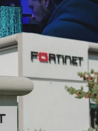 Image shows Fortinet office in the front and a cybercriminal hacking into systems in the background.