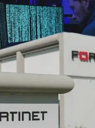 fortinet data leaked for free. image shows fortinet office in the front and a cybercriminal kacking into systems in the background