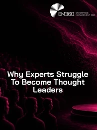 EM360Tech header graphic titled “Why Experts Struggle To Become Thought Leaders.” A lone speaker stands on a circular stage facing a large audience seated in darkness. Pink and magenta light swirls behind the speaker against a black background, creating a dramatic contrast. The EM360 Enterprise Management 360 logo appears in the top right corner.