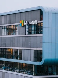 Closeup of big, grey office building with Microsoft logo displayed on the side.