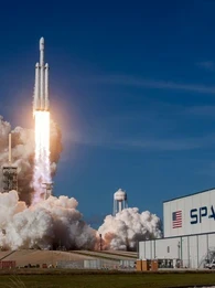 Rocket takes off with a plume of smoke on a blue sky on the SpaceX premises.