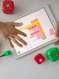 A child learning on a tablet with toys laying all around them.