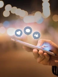 Person using a smartphone with Facebook reaction emojis floating above the screen