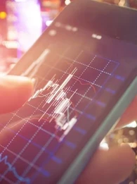 Someone using a smartphone checking stocks with a graph on a downward trend