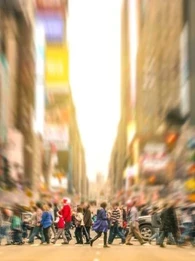 People crossing a busy road by Times Square in New York City, with a blurry cityscape background