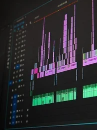 Audio editing software displaying multiple coloured waveform tracks on a dark interface.