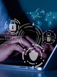 A close up of hands typing on a laptop with security icons floating around.
