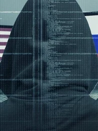 Back of a hacker in a black hoodie looking at two screens, one with the USA flag and the other with the Russia flag