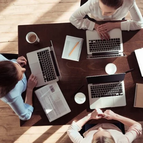 Colleagues working on laptops sharing a desk