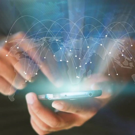 Person holding a smartphone with a see-through global map imposed on it.