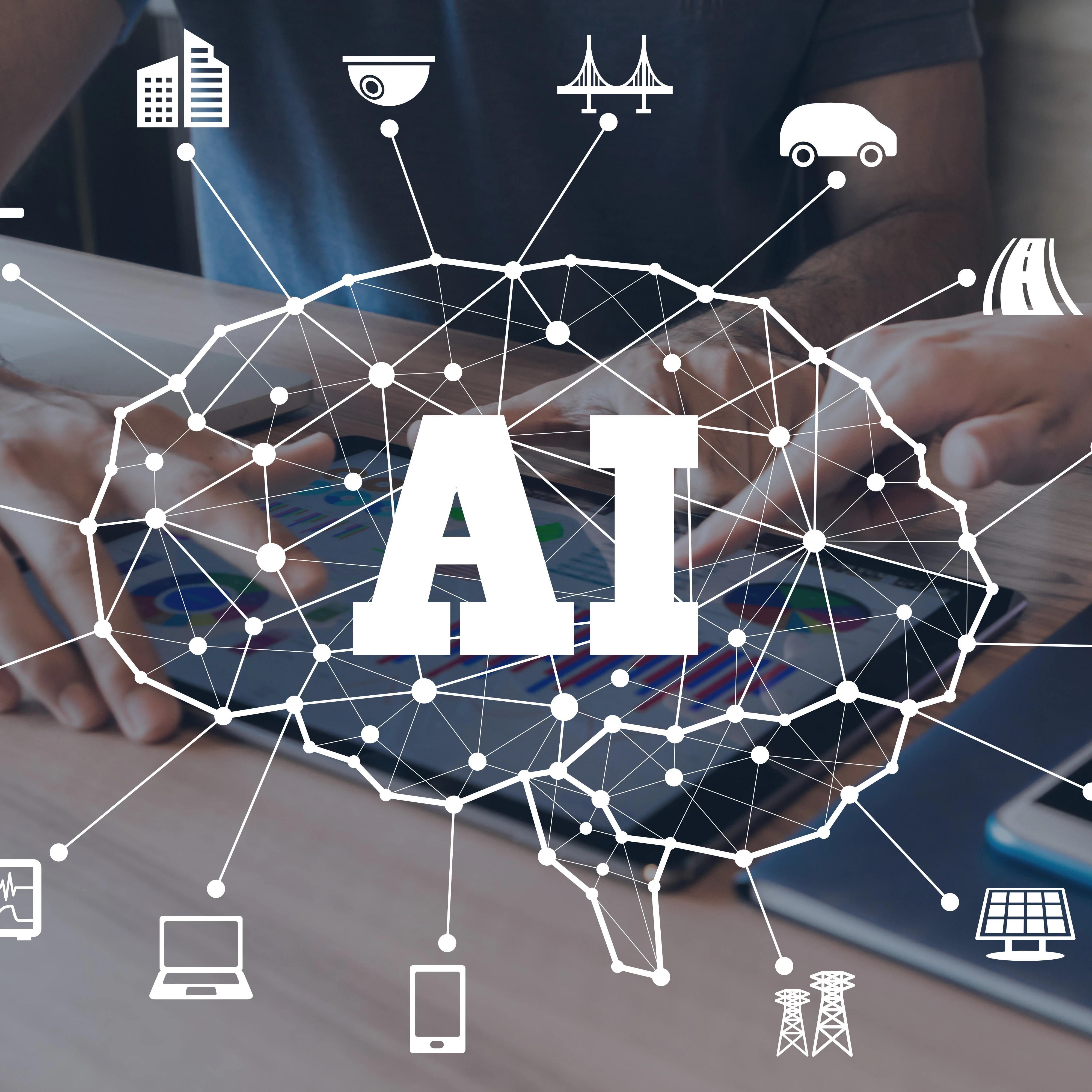Image depicting various technology-related icons around a brain and the letters "AI" against a background of people using a tablet at a desk.