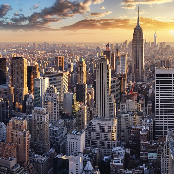 Aerial view of city skyscrapers with a sunset in the background.