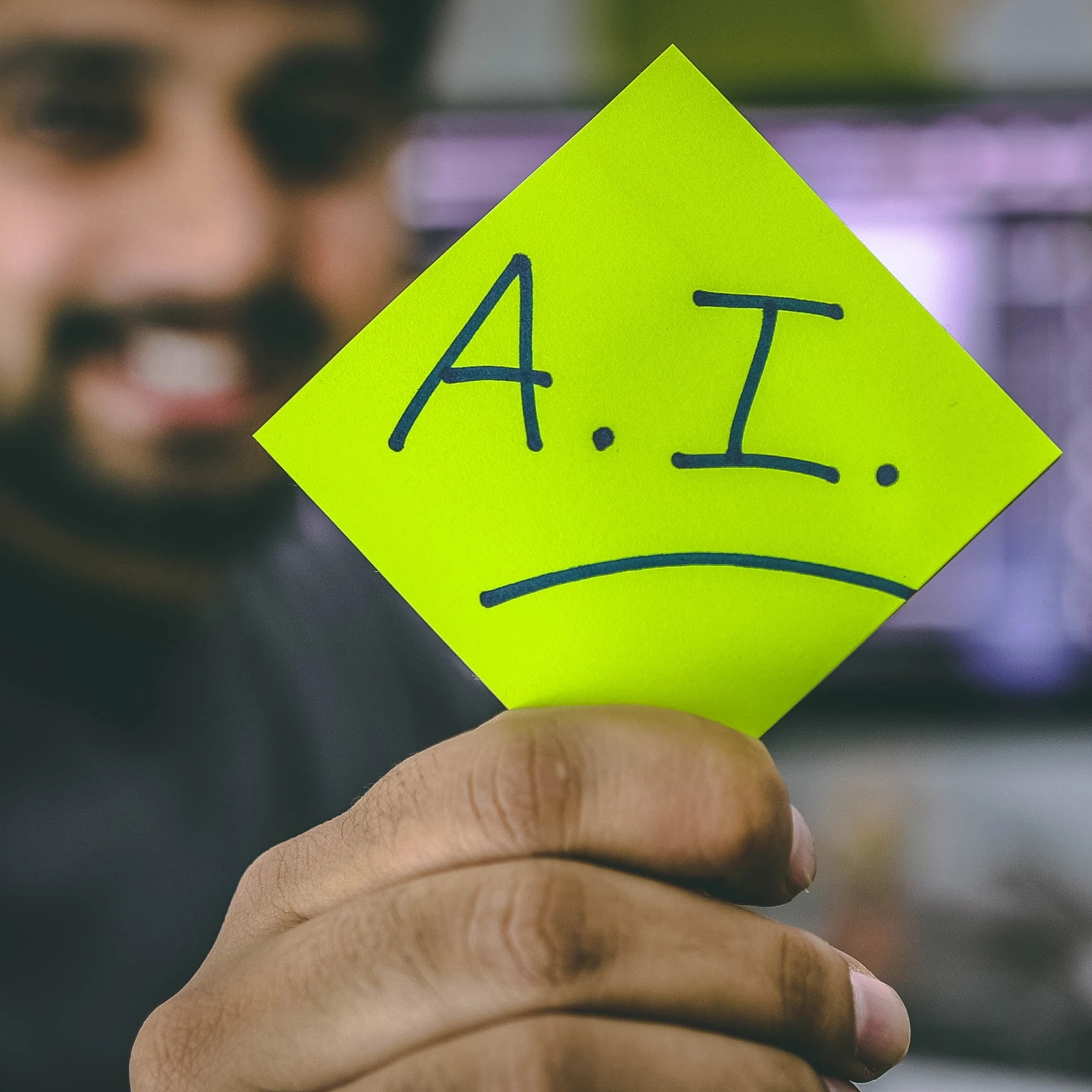 Person holding up a highlighter yellow paper with the words "A.I." on it.