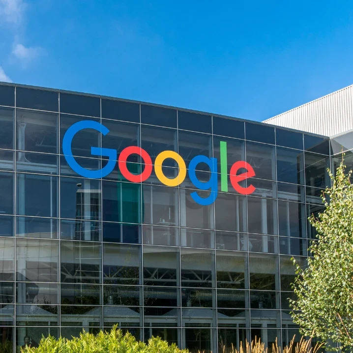 Google logo on the side of a building with lush greenery in front of it.