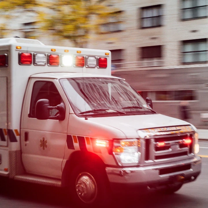 Ambulance driving down a city road with sirens and lights on.