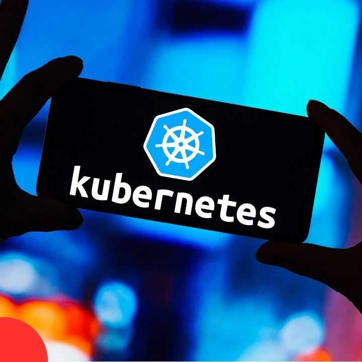 Hands holding up a smartphone with the screen displaying the word "Kubernetes"