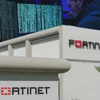 fortinet data leaked for free. image shows fortinet office in the front and a cybercriminal kacking into systems in the background