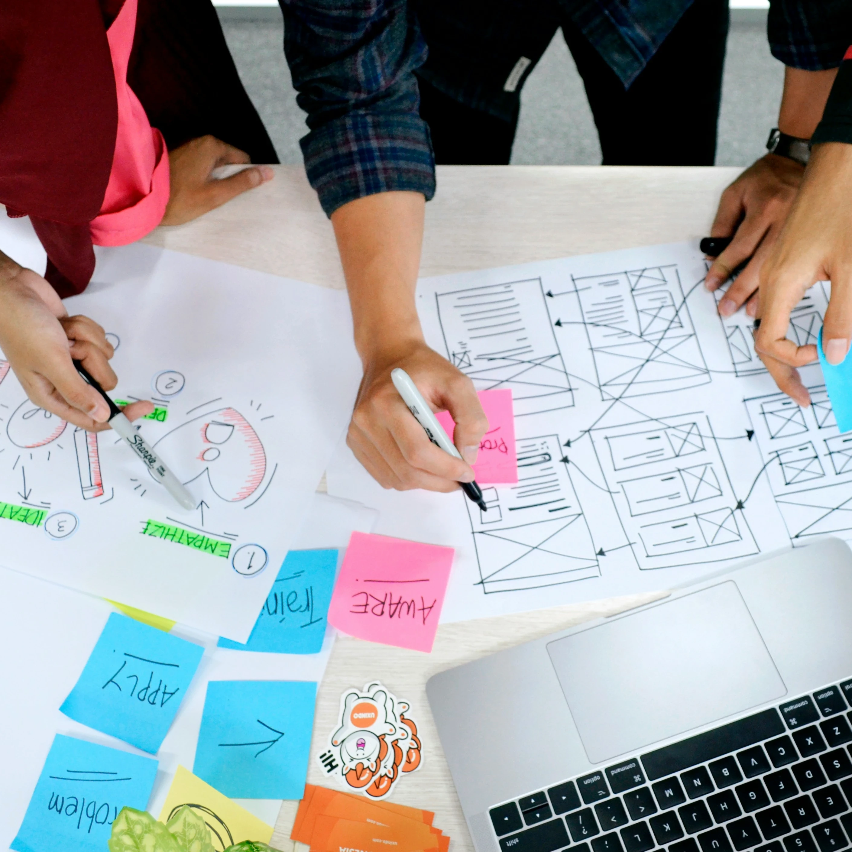 A group of people using colourful sticky notes, markers and a laptop to map out user experience.