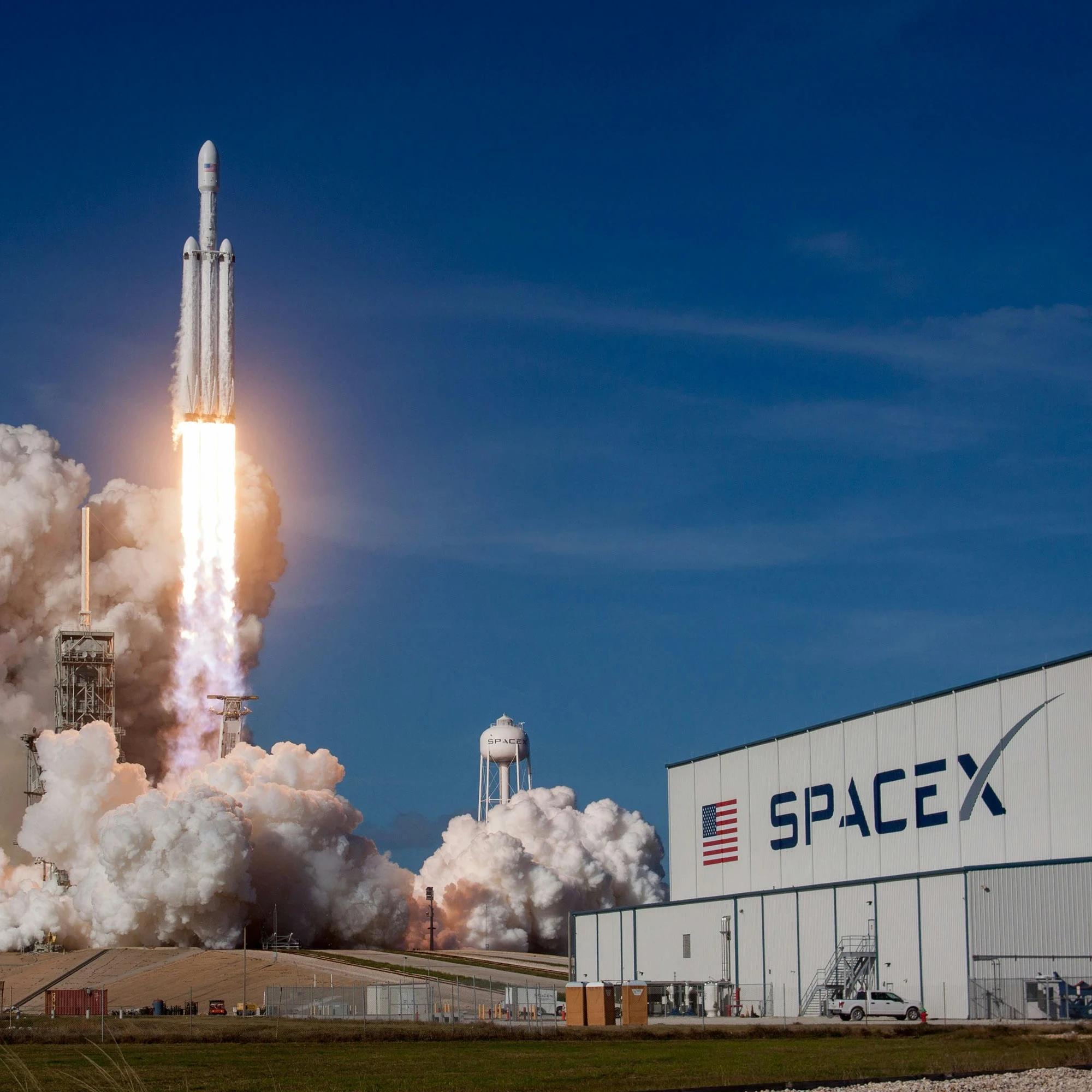 Rocket takes off with a plume of smoke on a blue sky on the SpaceX premises.