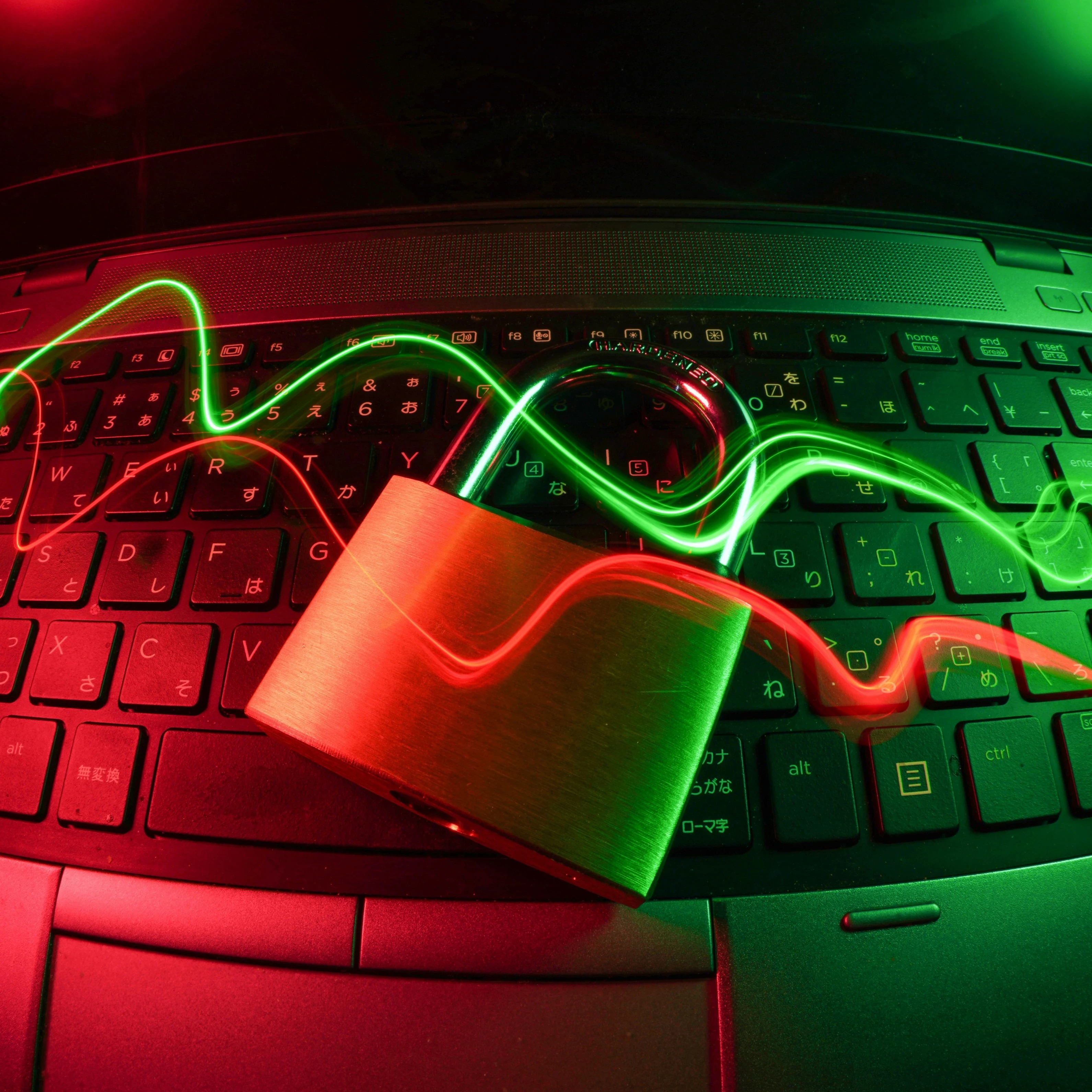An image depicting a closed lock laying on a laptop keyboard with red and green swirls flowing across.