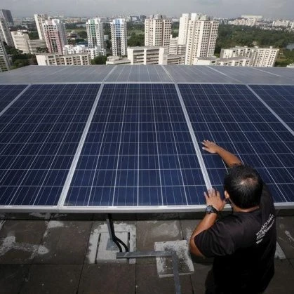Engineer fitting solar panels to the roof of a skyscraper with the Singapore cityscape in the background