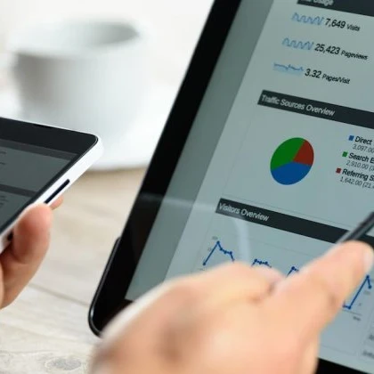 Person using a smartphone and pointing at a screen with charts on it.