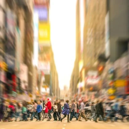 People crossing a busy road by Times Square in New York City, with a blurry cityscape background