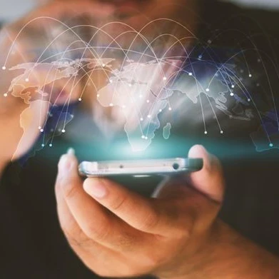A person holding a smartphone while a graphic of the world's countries floats above the screen with various connecting lines from country to country