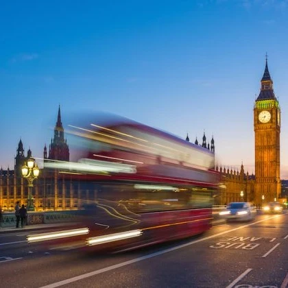 Image of London's Big Ben with a London red bus zooming past