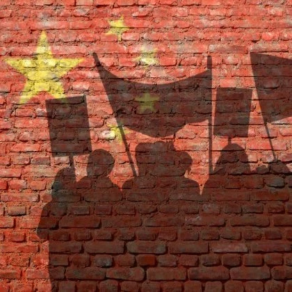 A shadow of a protesting crowd with banners against a brick wall with the EU logo on it in yellow