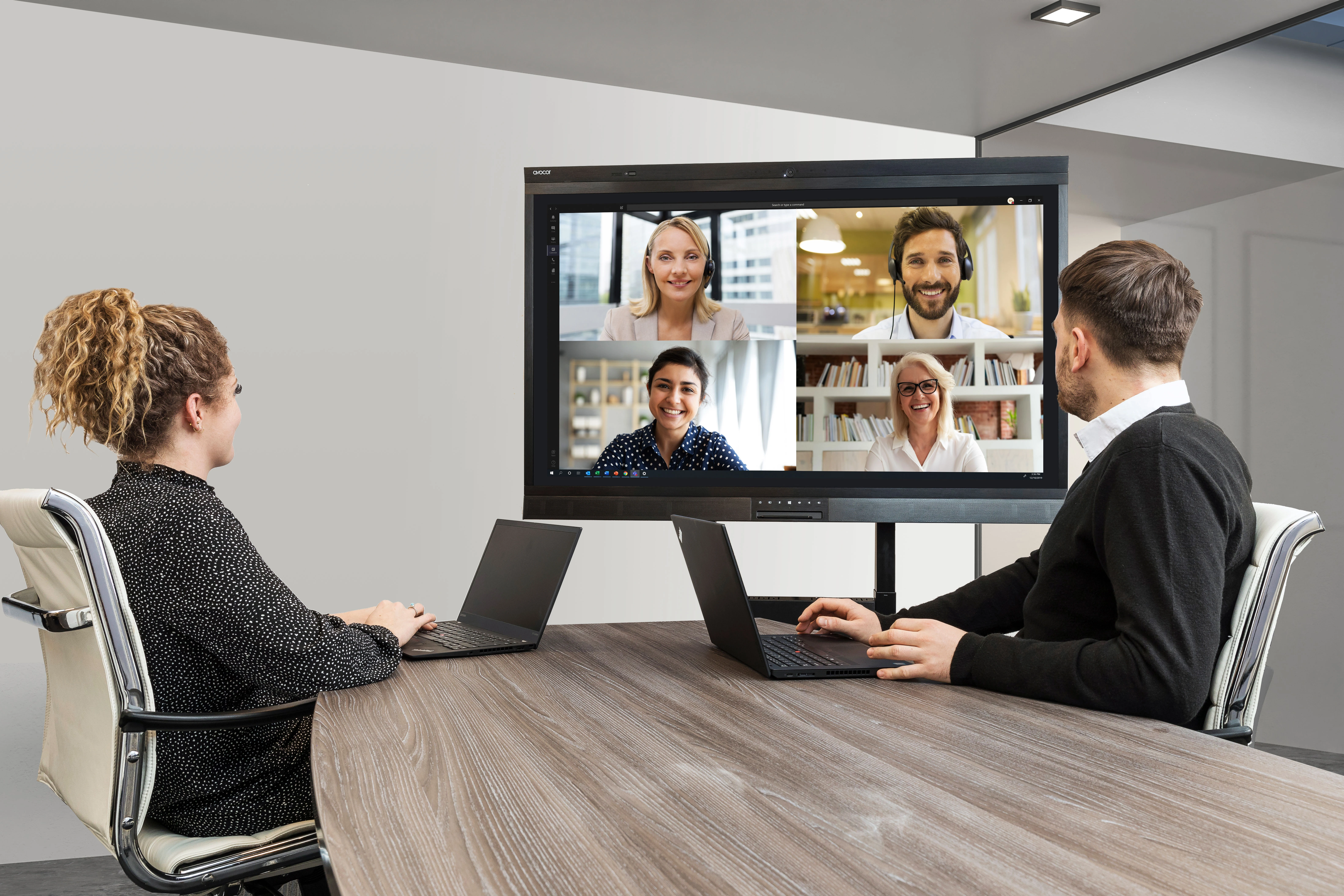 Hybrid meeting in progress. Two participants join the meeting from laptops in a meeting room, while four remote participants appear on a Avocor display