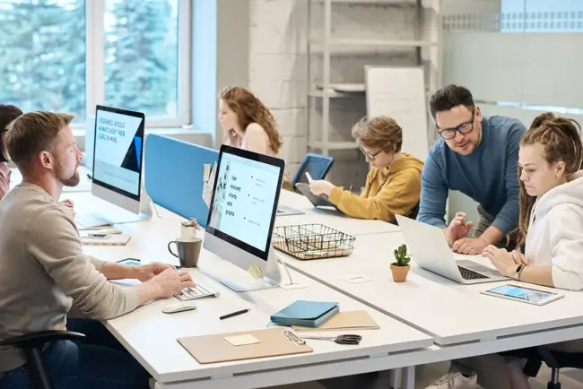 Employees sat at a large desk working on computers in a modern office